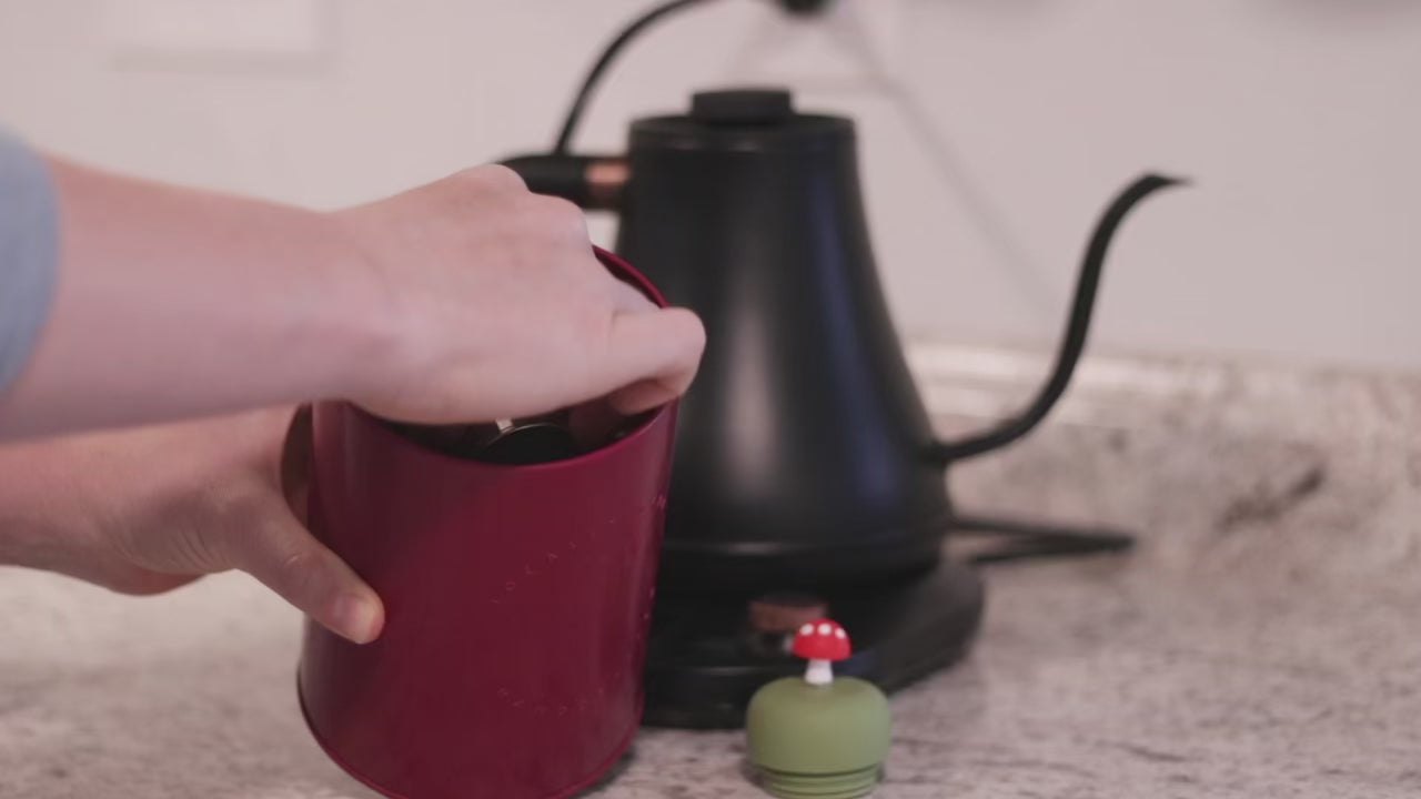 Load video: person uses tea basket to scoop tea leaves. Person pushes the silicone top onto the basket. Person adds the fully assembled tea infuser to a glass mug. person pour hot water into the glass mug. The Foating Tea Steeper immediately begins to infuse the water to make tea.